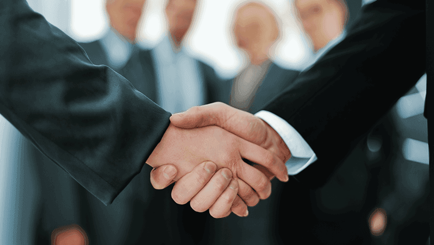 Два чоловіка, які потискають руки на діловій зустрічі, на розмитому фоні люди