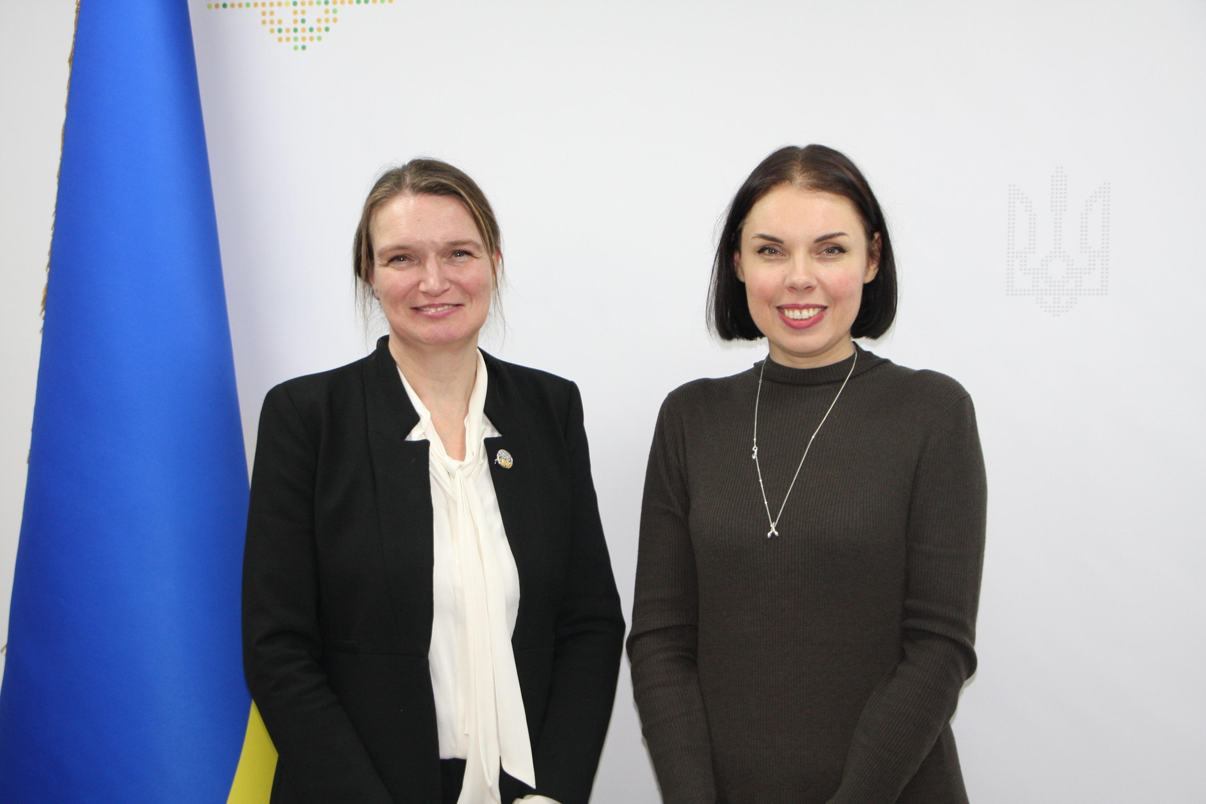 Двоє жіно стоять на фоні жовто-блакитного прапору