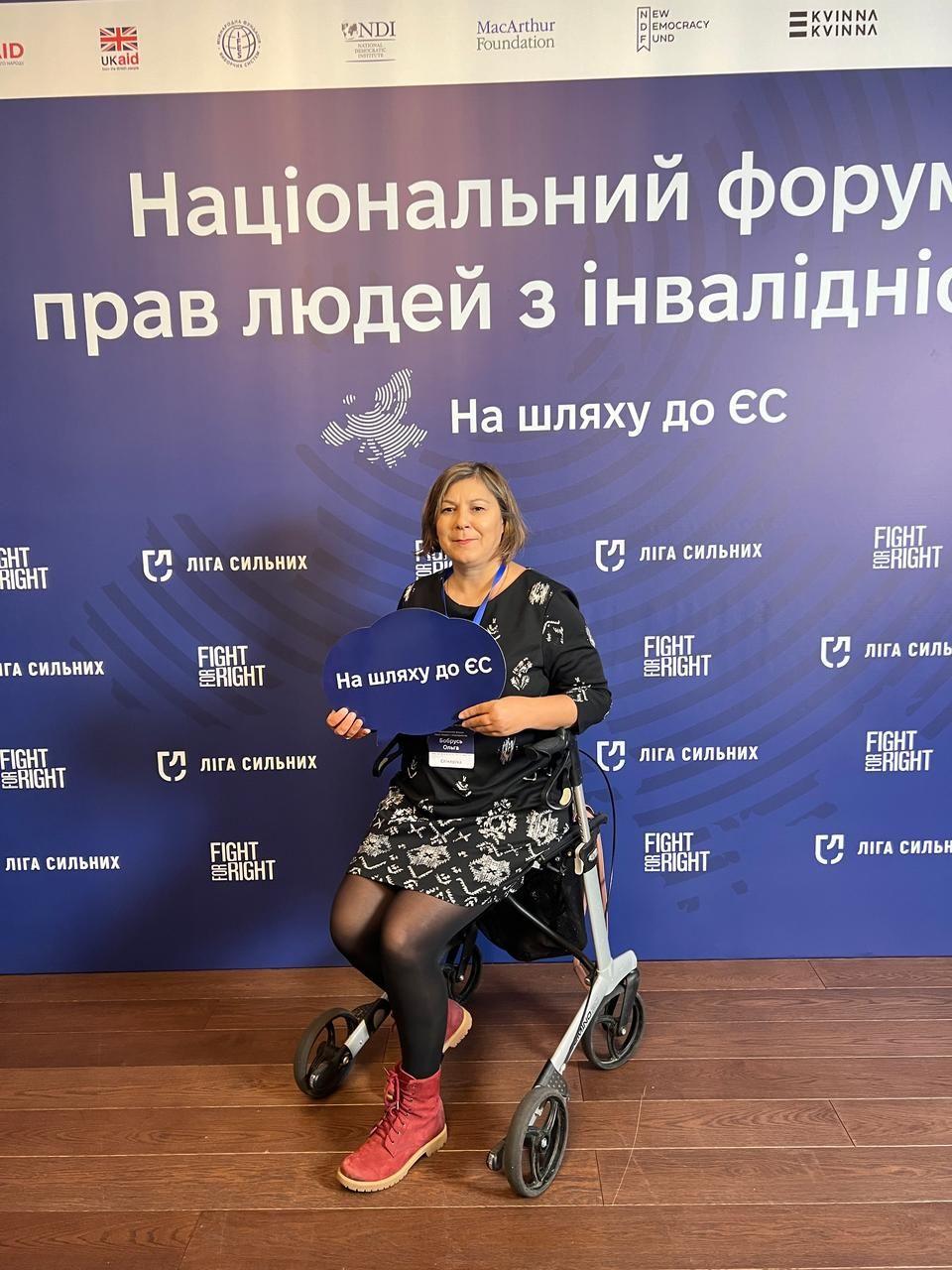 На зображенні жінка на ходунках з колесами.