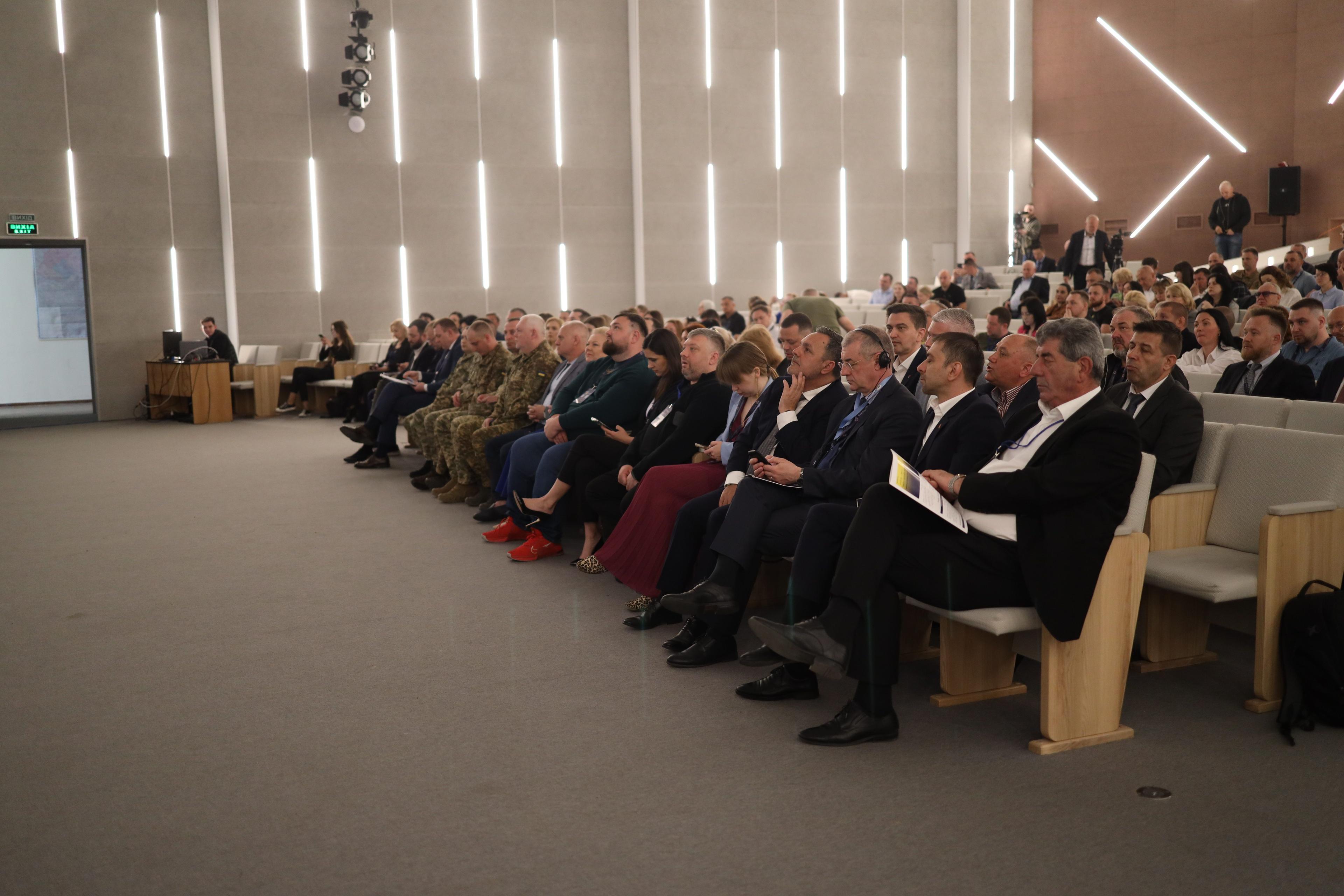На зображенні багато людей сидять в залі