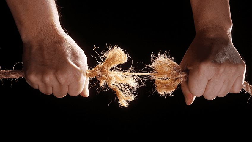 Дві руки тягнуть канат в протилежні боки, канат починає рватися в середині. Зображення символізує конфлікт або напруження. Дві руки тягнуть канат в протилежні боки, канат починає рватися в середині. Зображення символізує конфлікт або напруження.