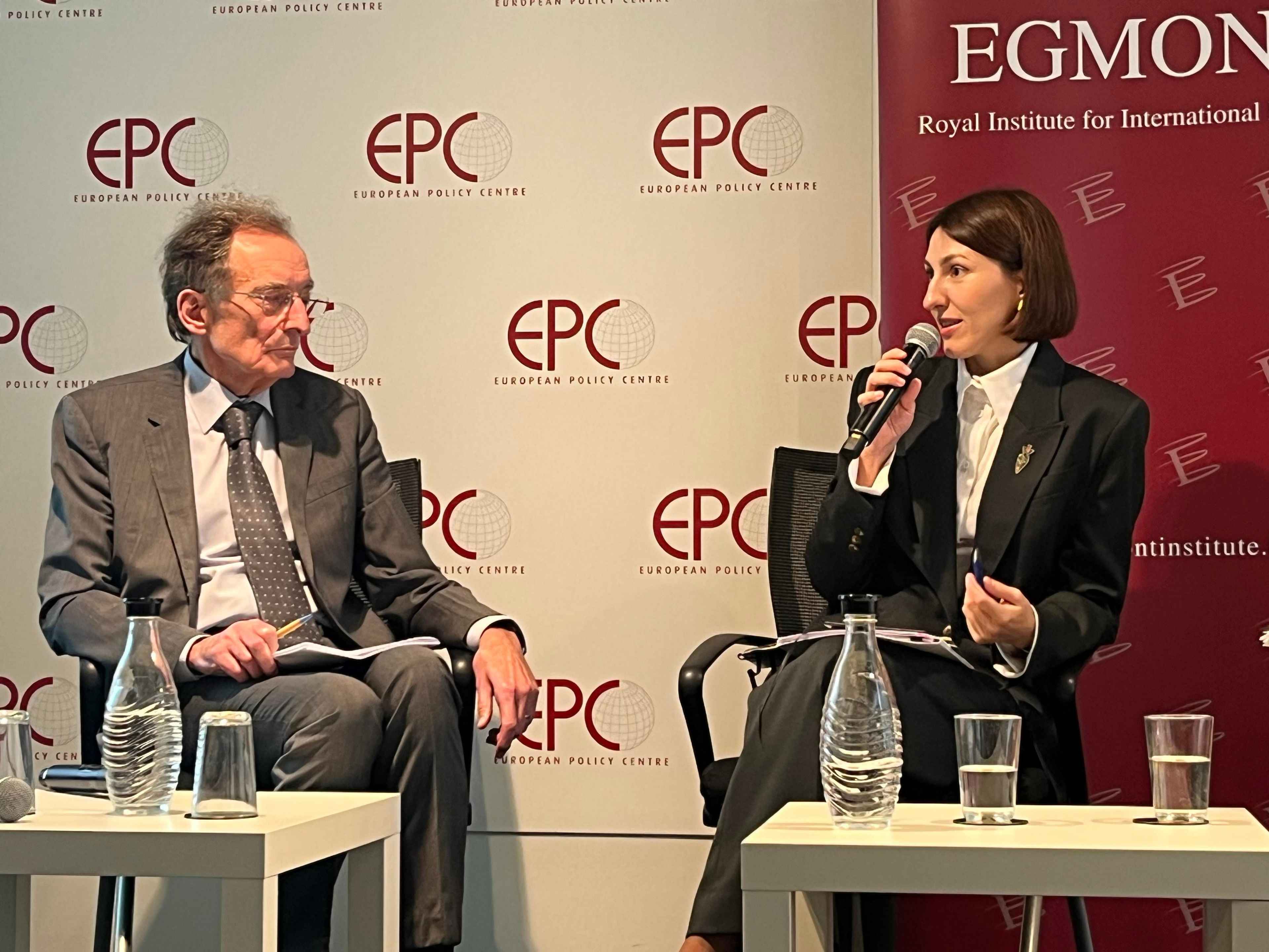 На фото чоловік і жінка сидять на фоні банеру під час заходу На фото чоловік і жінка сидять на фоні банеру під час заходу