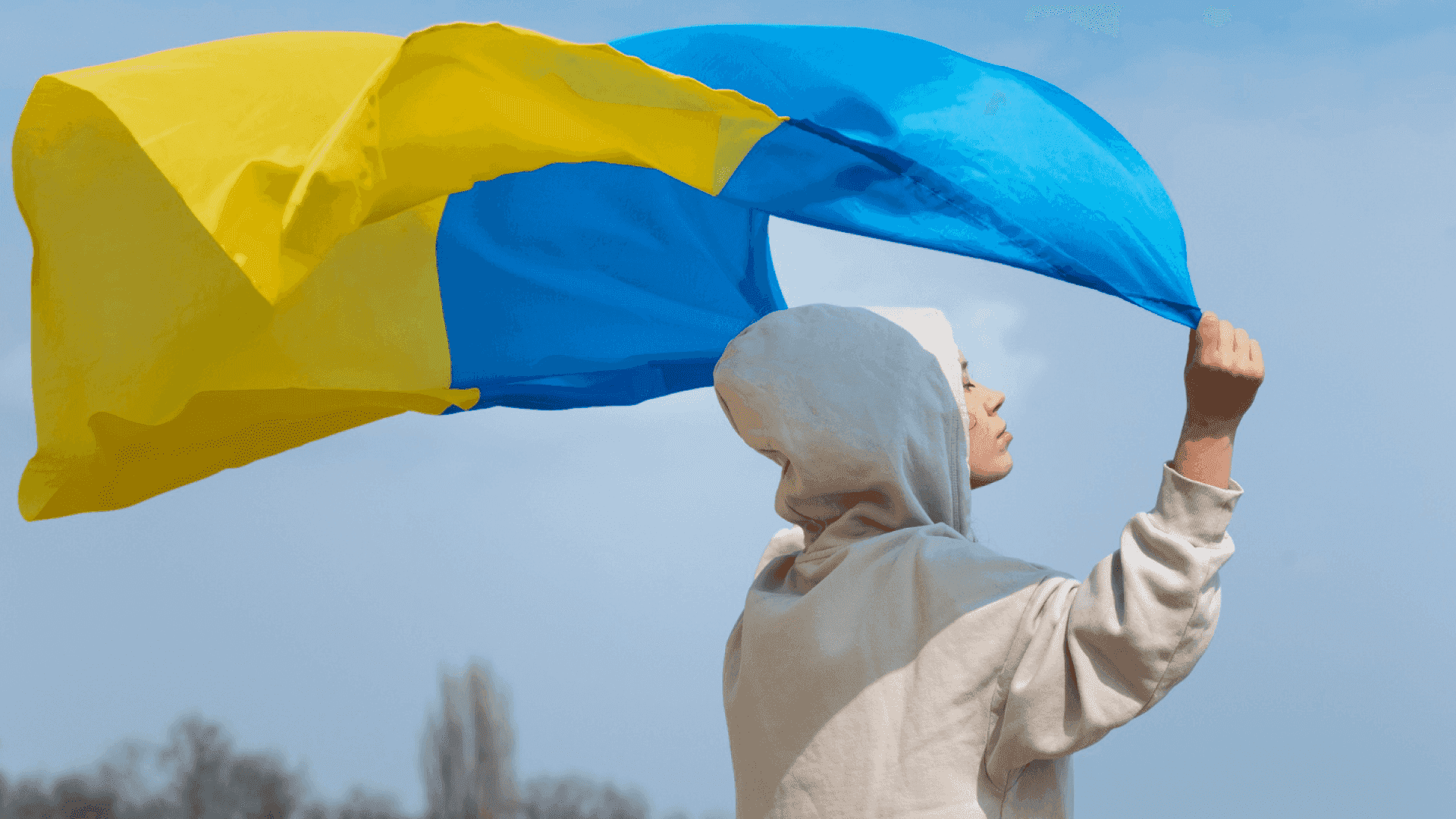 На фото зображено хлопця, який тримає над собою прапор України На фото зображено хлопця, який тримає над собою прапор України