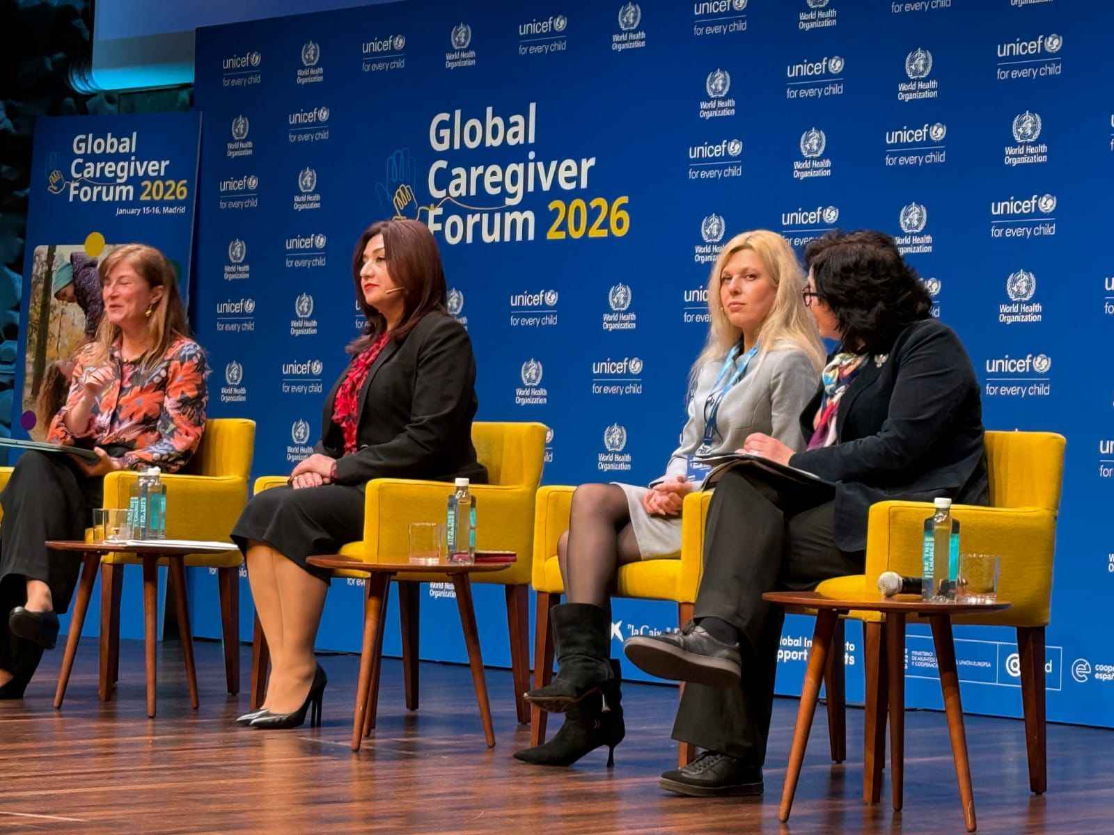 На фото жінки сидять на фоні сцени під час заходу На фото жінки сидять на фоні сцени під час заходу