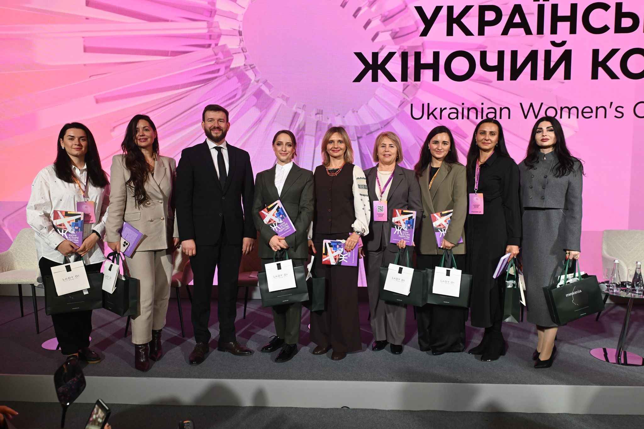 На фото жінки та чоловік стоять на фоні банеру На фото жінки та чоловік стоять на фоні банеру