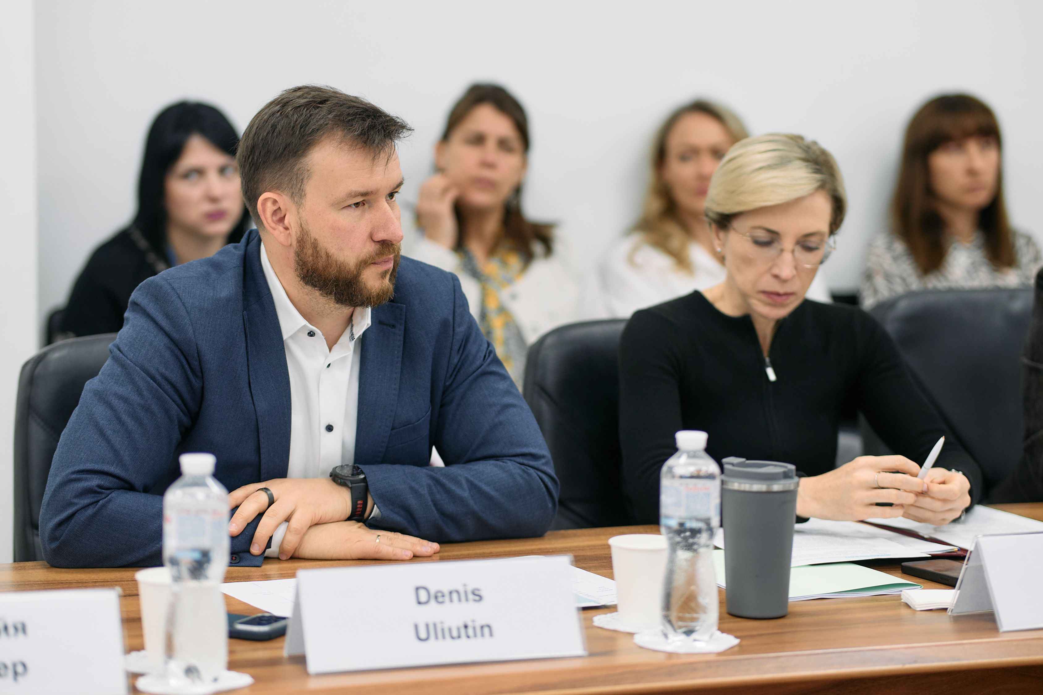 На фото жінка та чоловік сидять за столом під час зустрічі На фото жінка та чоловік сидять за столом під час зустрічі
