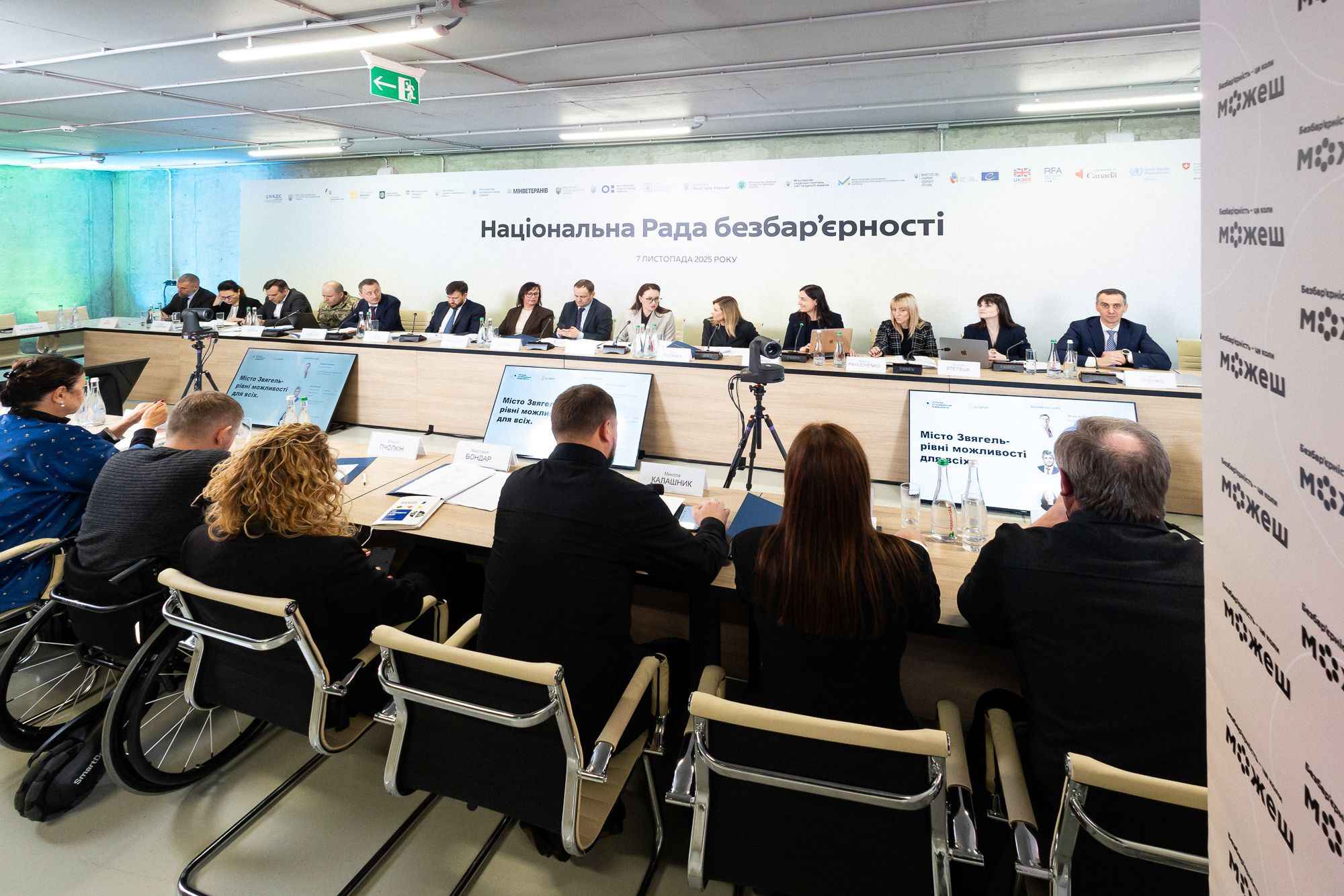 На фото чоловіки та жінки сидять за столом під час заходу На фото чоловіки та жінки сидять за столом під час заходу