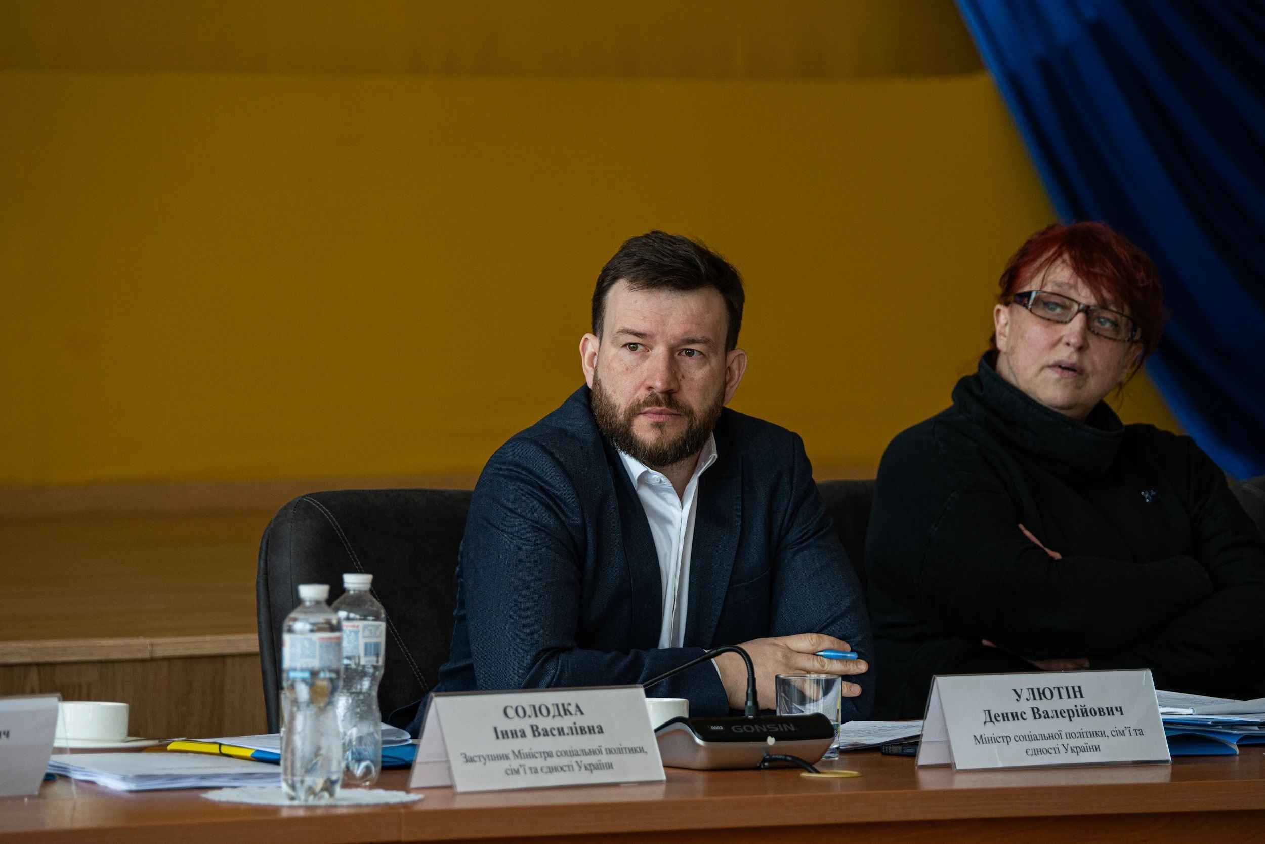 На фото чоловік та жінка сидять за столом під час слухань На фото чоловік та жінка сидять за столом під час слухань