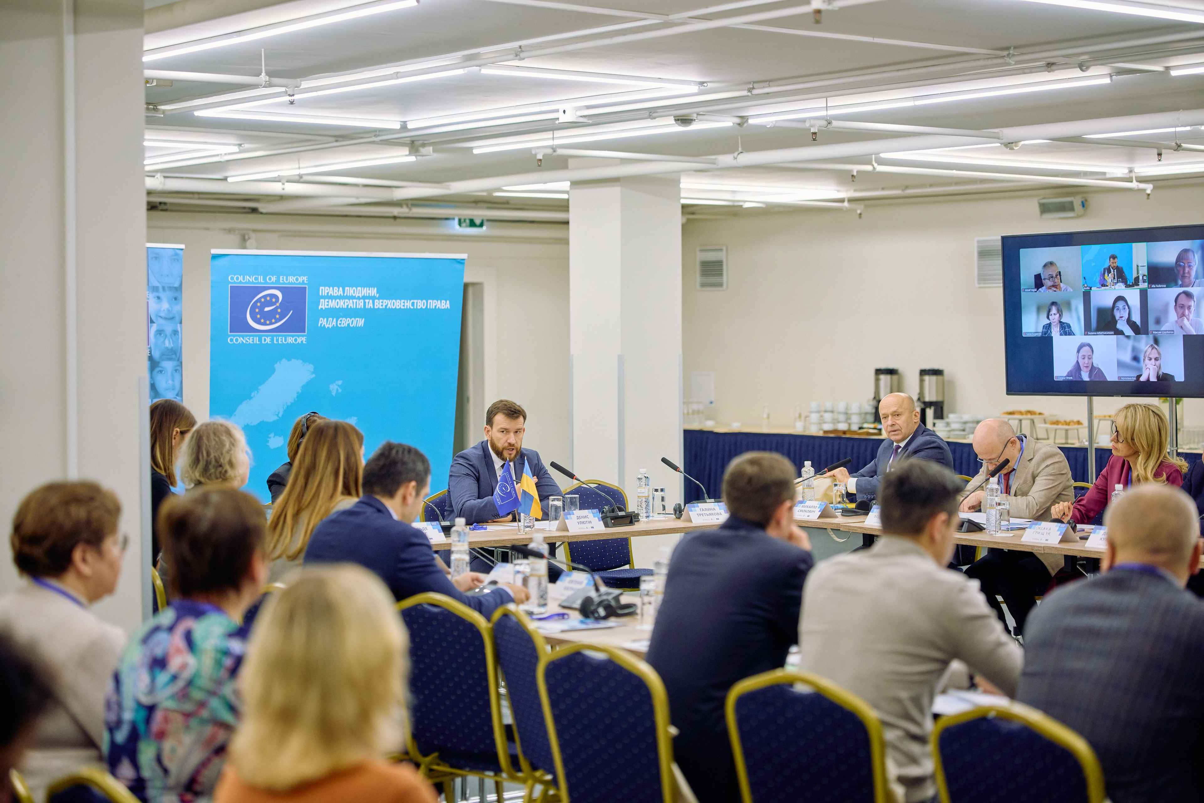 На фото жінки та чоловіки сидять за столом під час заходу На фото жінки та чоловіки сидять за столом під час заходу