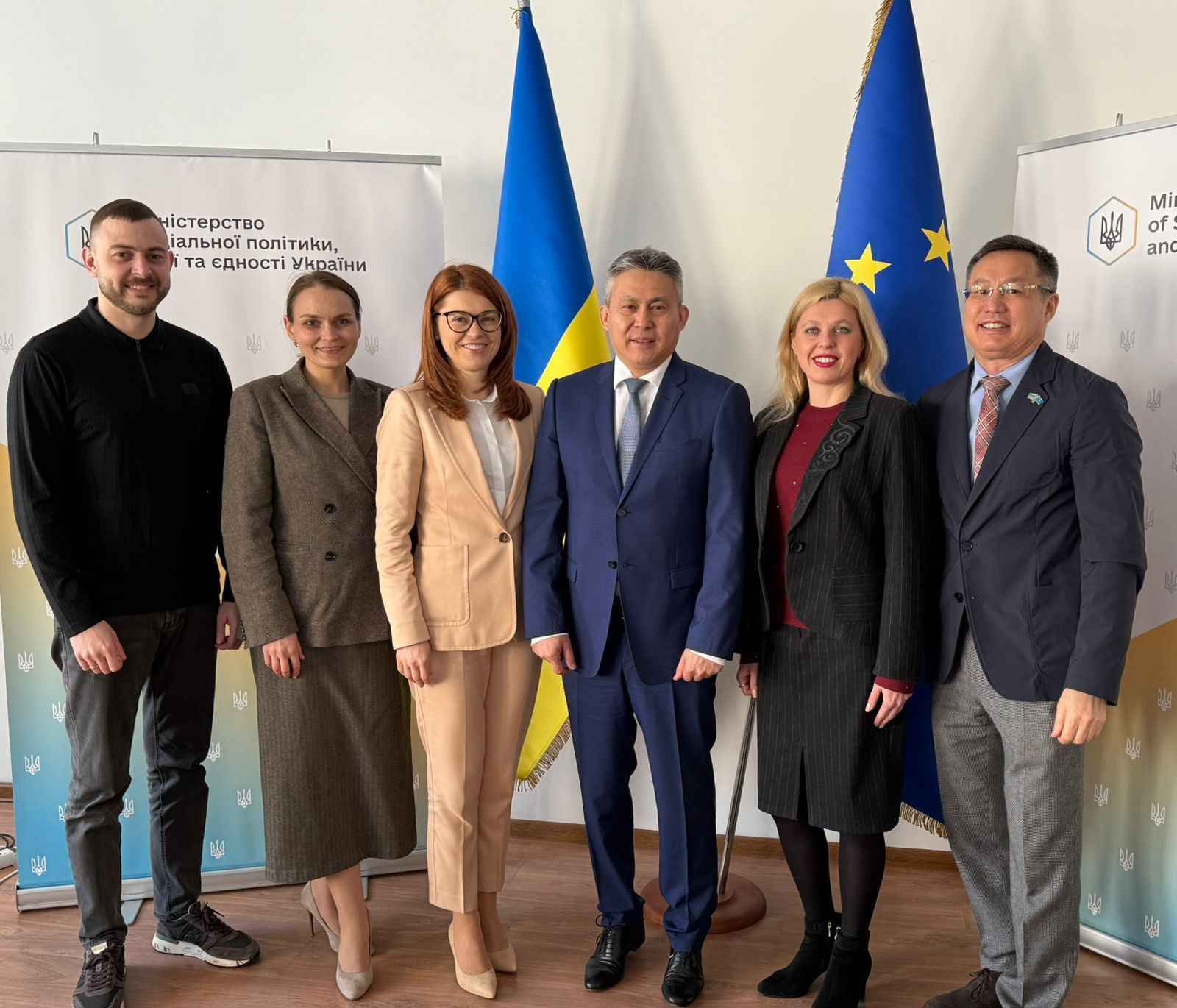 На фото чоловіки та жінки стоять на фоні прапорів України та ЄС На фото чоловіки та жінки стоять на фоні прапорів України та ЄС